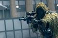 Screenshot of Modern Warfare player wearing a ghillie suit holding a sniper rifle with a throwing knife flying towards them